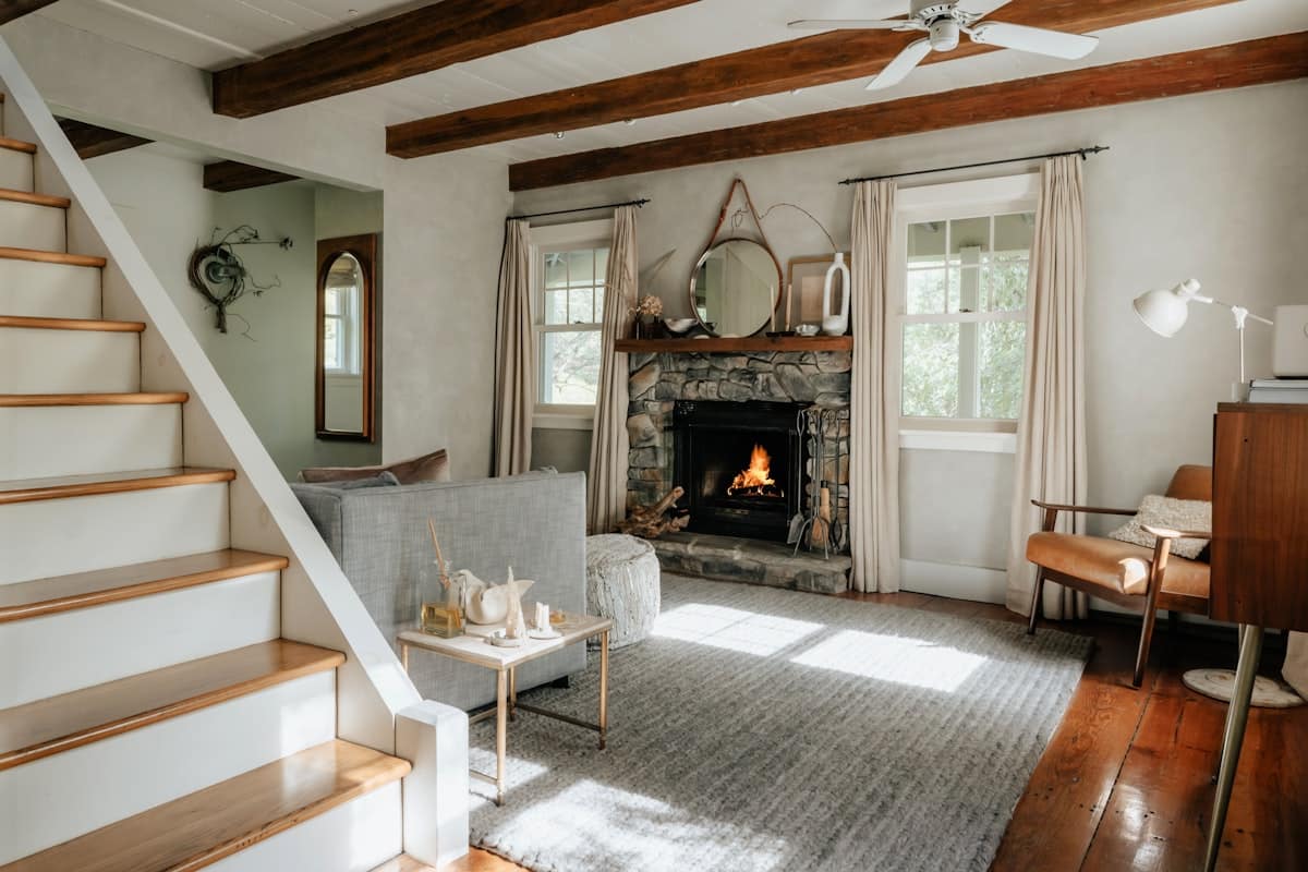 Designed Cle Elum WA living room with exposed beams, stone fireplace, drapery and layered furnishings